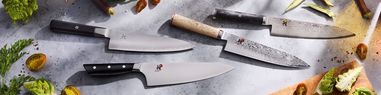 Miyabi chef&rsquo;s knives from several collections on a stone surface