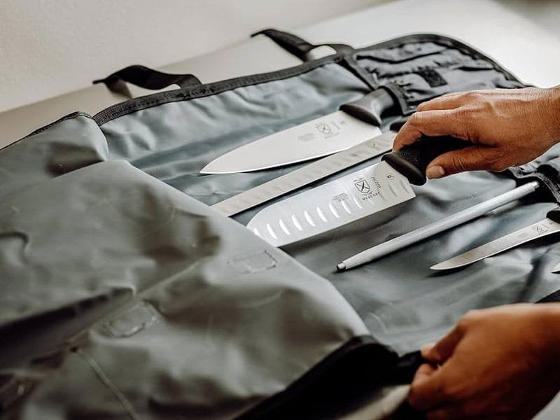 Professional knife roll opened with knives secured in individual slots