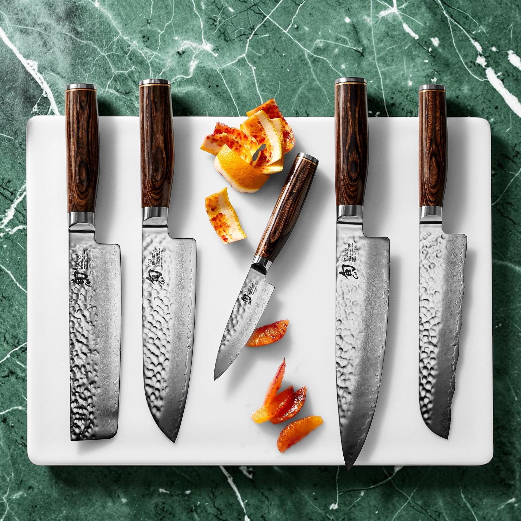 Shun Premier knives with hammered blades and walnut-colored handles on a wood cutting board